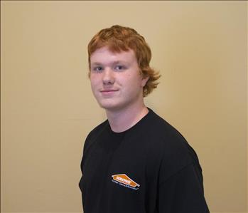 Male employee with red hair in front of tan background