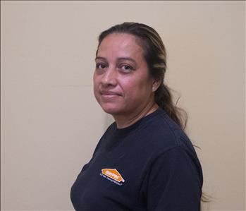 Female employee with black hair in front of tan background