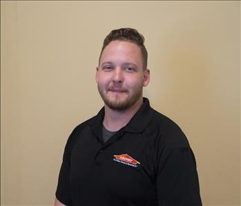 Male employee with brown hair in front of gray background